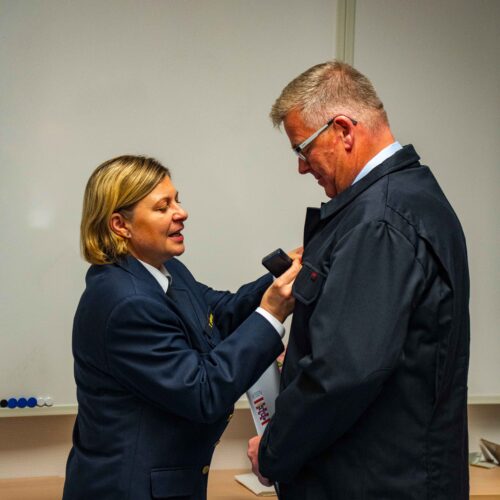 Kreisbrandinspektorin Tanja Dittmar steckt Bernd Lengemann das goldene Brandschutzehrenzeichen an