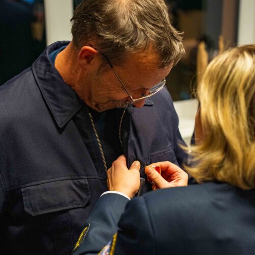 Kreisbrandinspektorin Tanja Dittmar steckt Mario Reiße das goldene Brandschutzehrenzeichen an